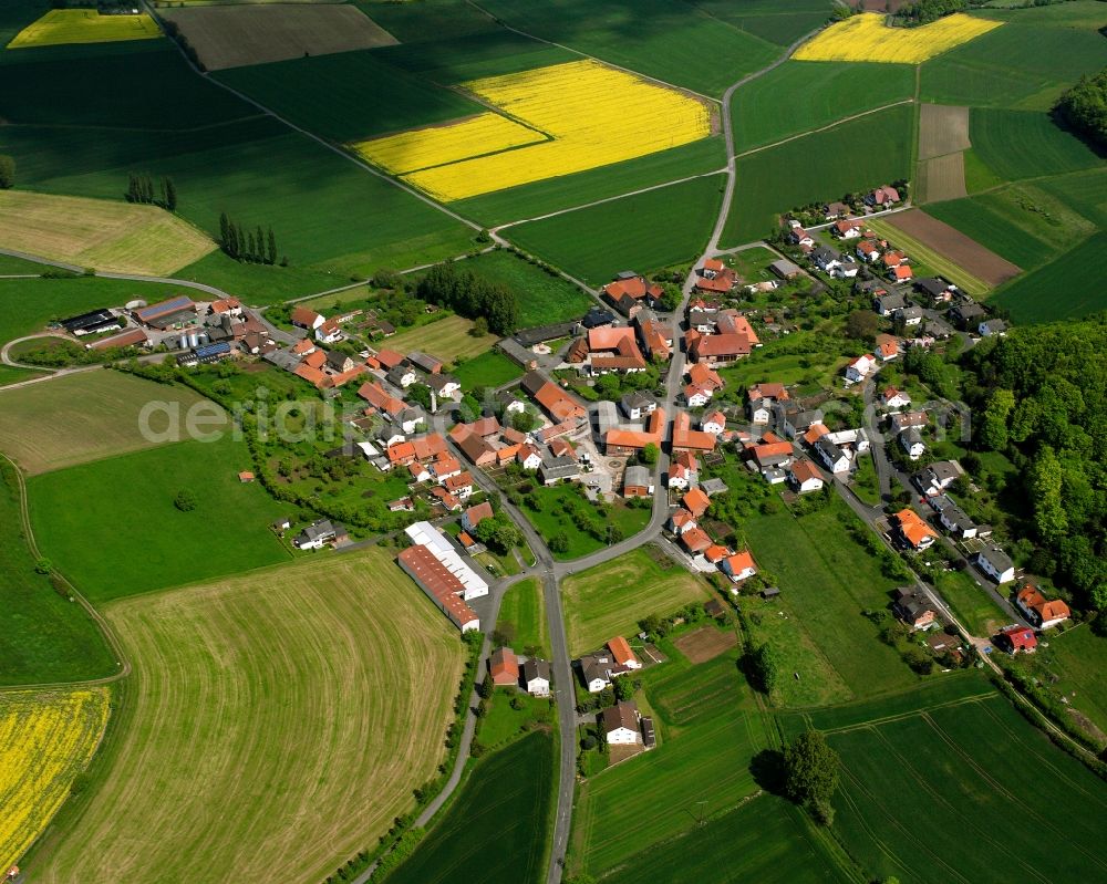 Wehrshausen from above - Agricultural land and field boundaries surround the settlement area of the village in Wehrshausen in the state Hesse, Germany