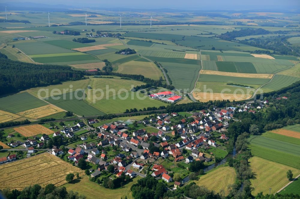 Haueda from above - Agricultural land and field borders surround the settlement area of the village in Haueda in the state Hesse, Germany