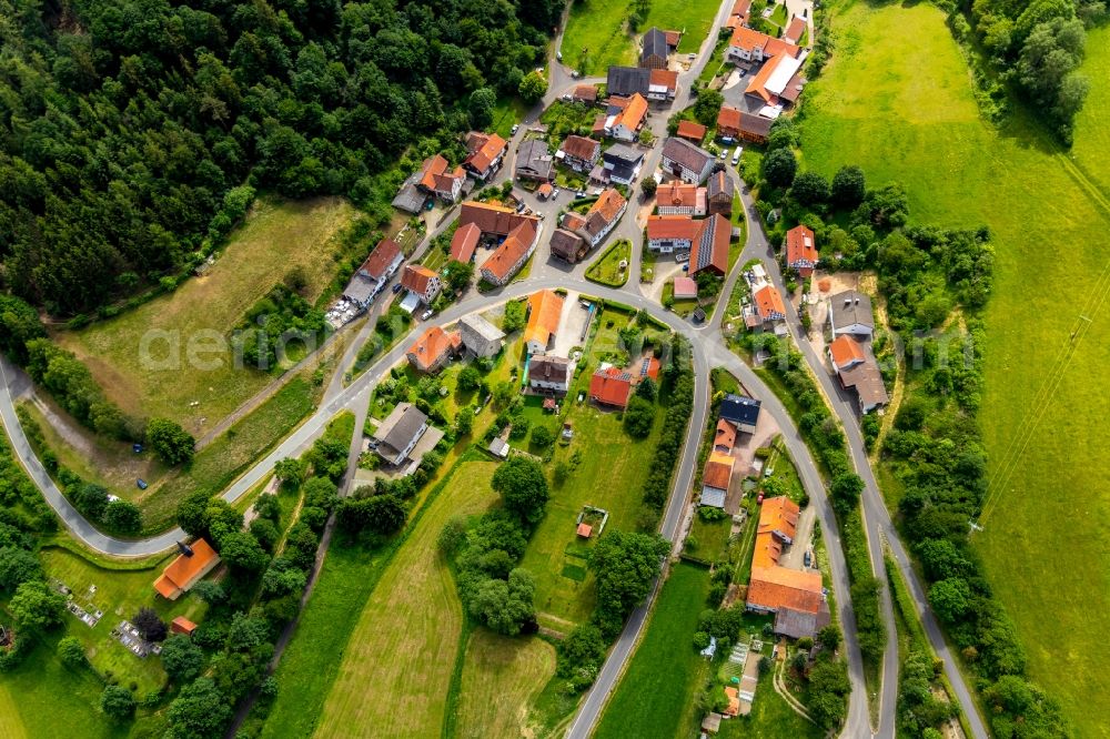 Hüddingen from above - Agricultural land and field borders surround the settlement area of the village in Hueddingen in the state Hesse, Germany