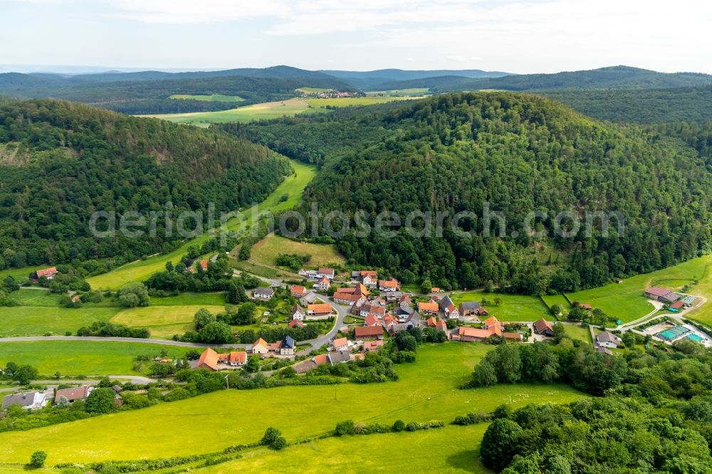 Hüddingen from the bird's eye view: Agricultural land and field borders surround the settlement area of the village in Hueddingen in the state Hesse, Germany