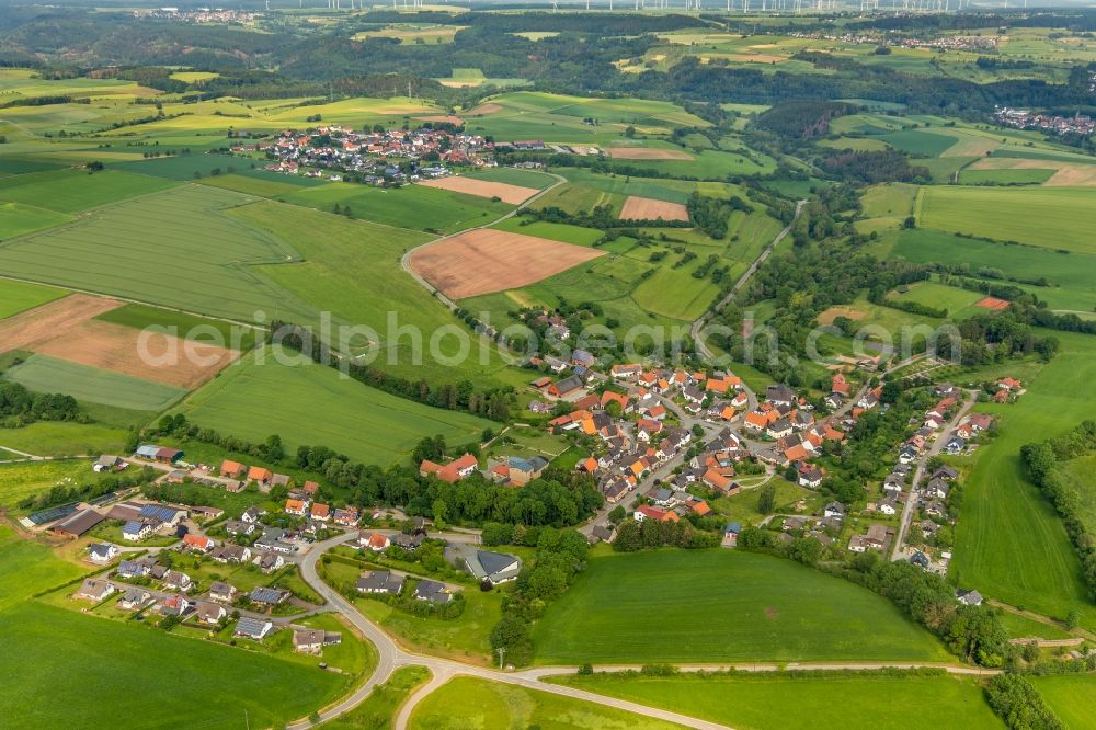 Helmighausen from the bird's eye view: Agricultural land and field borders surround the settlement area of the village in Helmighausen in the state Hesse, Germany