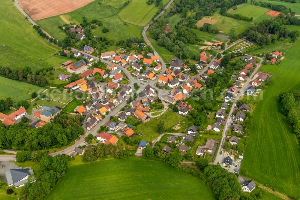 Helmighausen from above - Agricultural land and field borders surround the settlement area of the village in Helmighausen in the state Hesse, Germany