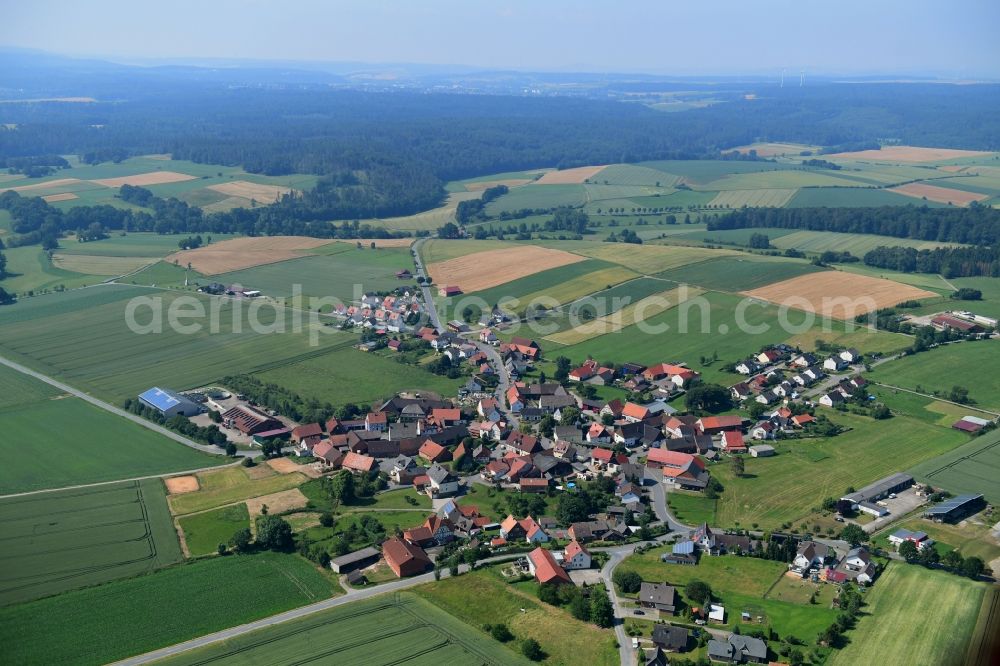 Herbsen from above - Agricultural land and field borders surround the settlement area of the village in Herbsen in the state Hesse, Germany