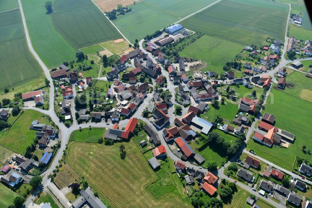 Herbsen from above - Agricultural land and field borders surround the settlement area of the village in Herbsen in the state Hesse, Germany