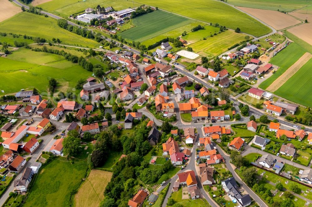 Hundsdorf from the bird's eye view: Agricultural land and field borders surround the settlement area of the village in Hundsdorf in the state Hesse, Germany
