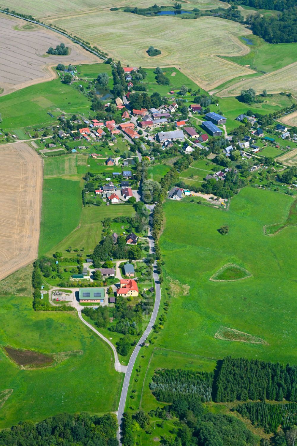 Lüttenhagen from the bird's eye view: Agricultural land and field borders surround the settlement area of the village in Luettenhagen in the state Mecklenburg - Western Pomerania, Germany