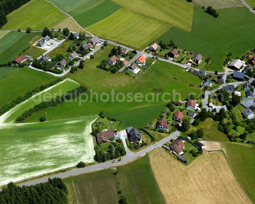 Aerial image Lippertsgrün - Agricultural land and field boundaries with the power plants surround the settlement area of the village in Lippertsgrün in the state Bavaria, Germany