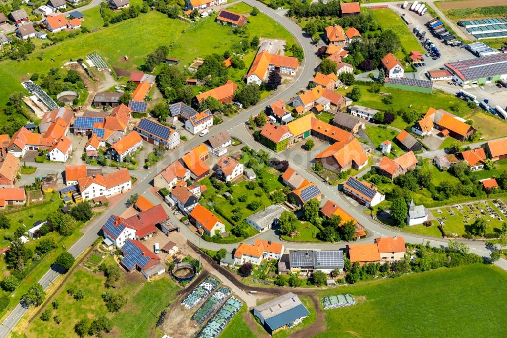 Rhadern from above - Agricultural land and field borders surround the settlement area of the village in Rhadern in the state Hesse, Germany