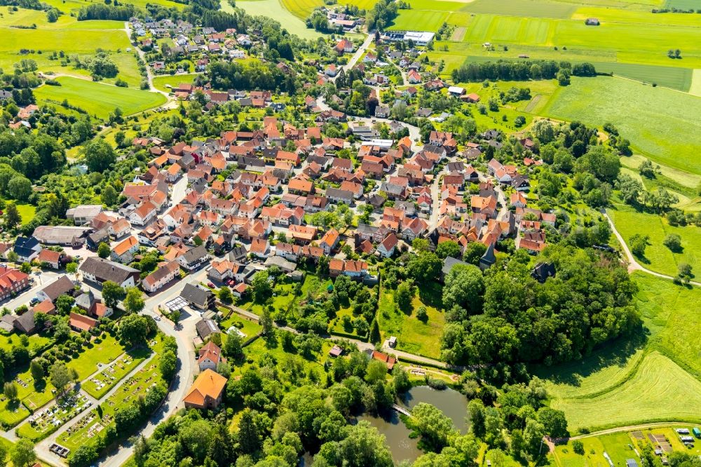 Sachsenberg from the bird's eye view: Agricultural land and field borders surround the settlement area of the village in Sachsenberg in the state Hesse, Germany