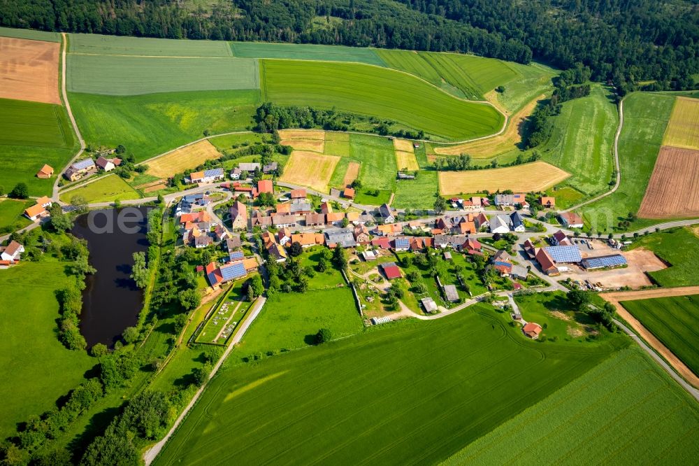 Volkhardinghausen from the bird's eye view: Agricultural land and field borders surround the settlement area of the village in Volkhardinghausen in the state Hesse, Germany