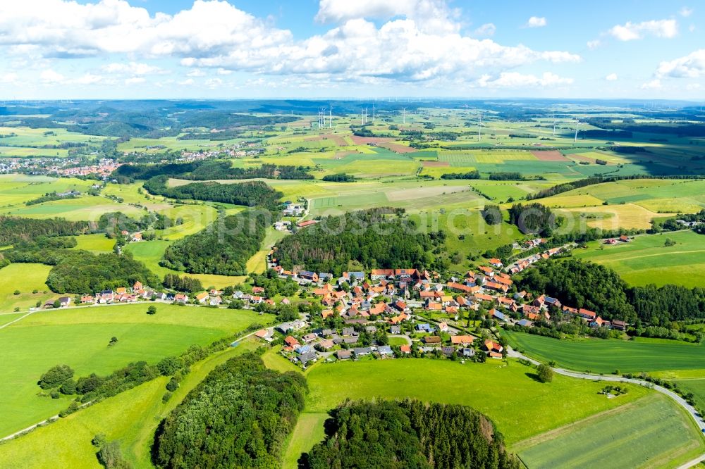 Wirmighausen from the bird's eye view: Agricultural land and field borders surround the settlement area of the village in Wirmighausen in the state Hesse, Germany