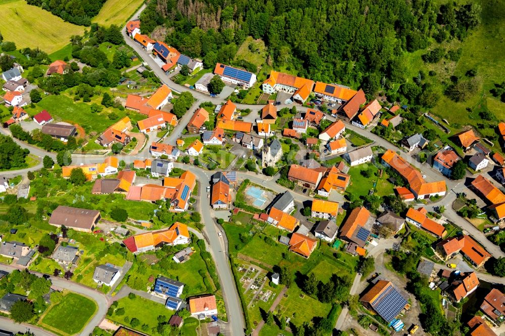 Wirmighausen from above - Agricultural land and field borders surround the settlement area of the village in Wirmighausen in the state Hesse, Germany