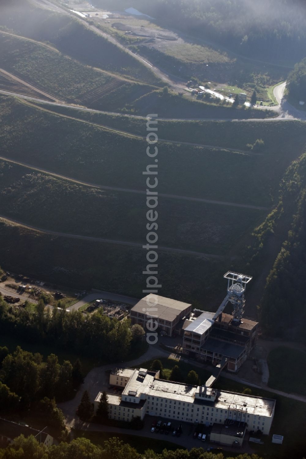 Aerial image Hartenstein - Former headframe and mining pit Schacht 371 of SDAG Wismut in the Poppenwald forest in the borough of Hartenstein in the state of Saxony. The pit was the main pit of the now disused mining company of Aue and is used as a museum of the mineral collection of Wismut GmbH