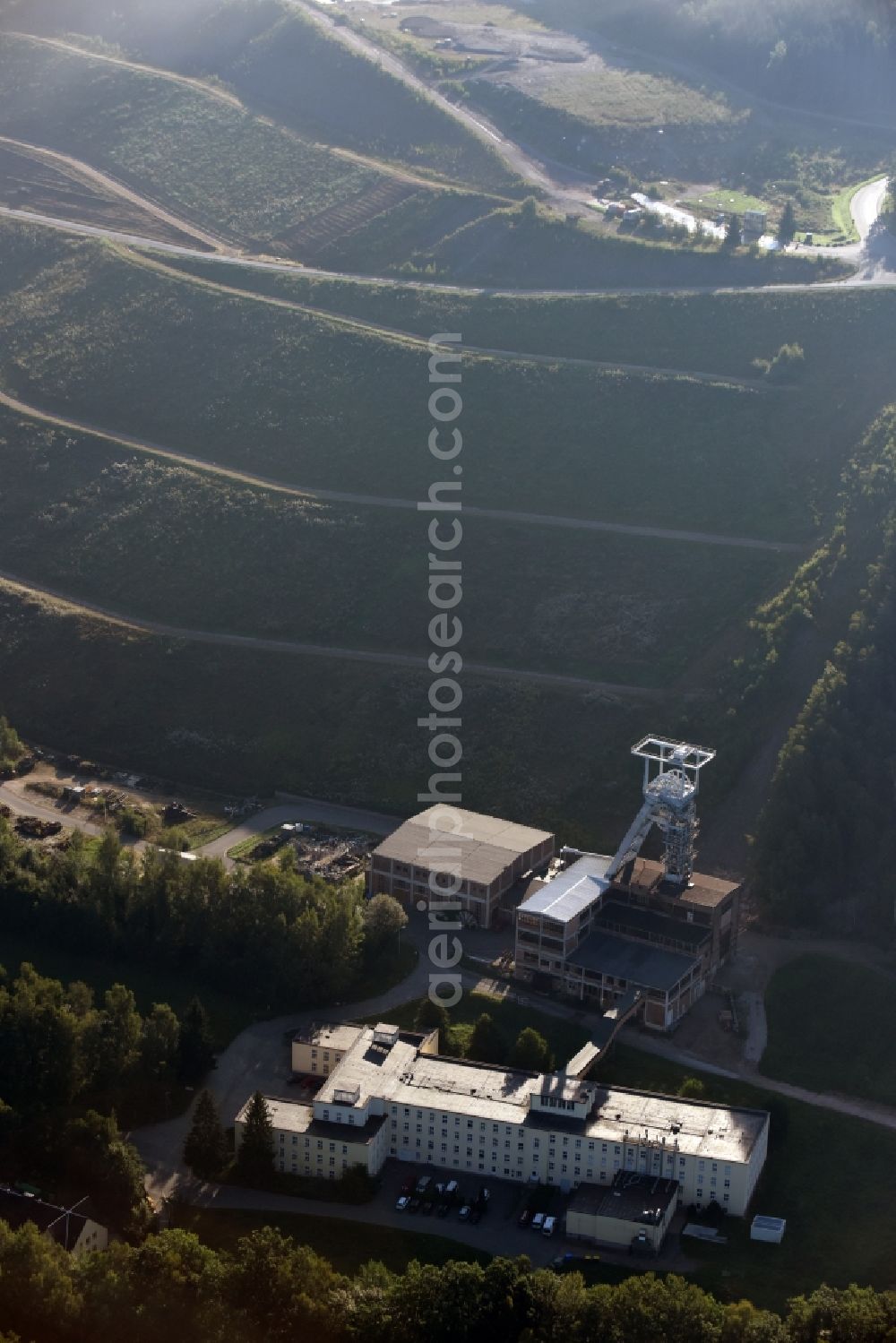 Aerial photograph Hartenstein - Former headframe and mining pit Schacht 371 of SDAG Wismut in the Poppenwald forest in the borough of Hartenstein in the state of Saxony. The pit was the main pit of the now disused mining company of Aue and is used as a museum of the mineral collection of Wismut GmbH