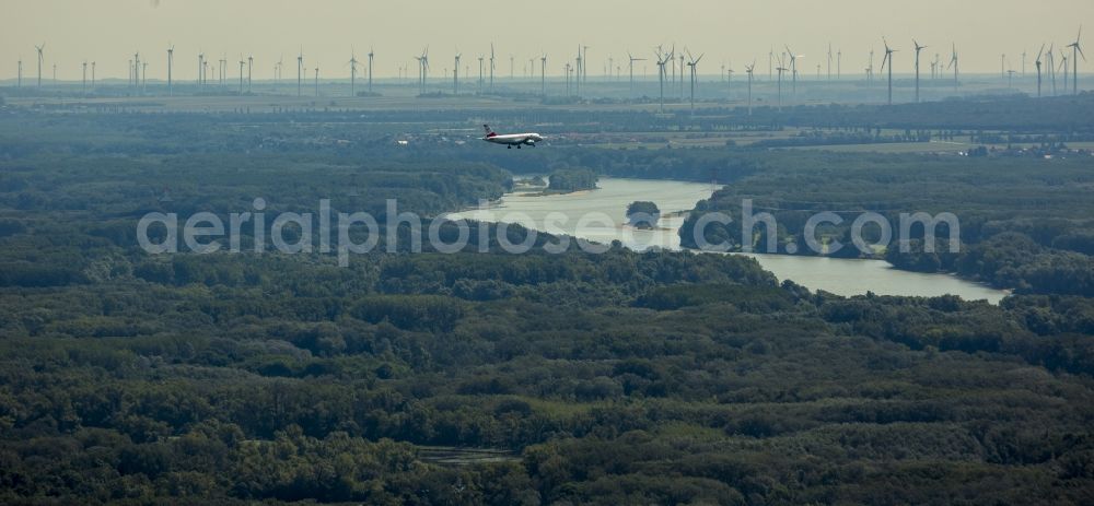 Wien from the bird's eye view: View of a low flying aircraft over a forestland near the Danube in Vienna in Austria. On the fields in the background the wind turbines of an onshore wind farm are visible