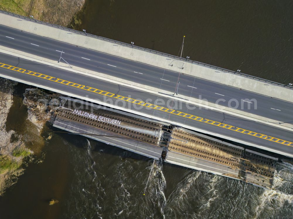 Dresden from above - Concrete segments fallen into the riverbed of the Elbe with the slogan Tax millionaires of the collapsed river bridge structure for crossing the Elbe Carolabruecke on the street Carolabruecke in Dresden in the federal state of Saxony, Germany