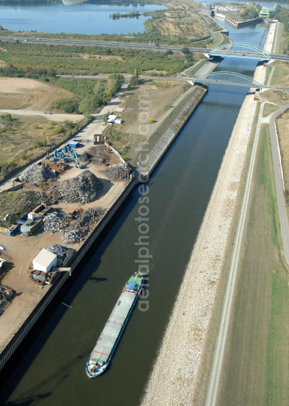 MAGDEBURG from above - Blick auf die Industriegebiete am Ufer des Elbe-Abstiegskanal, der den Magdeburger Binnen- Hafen mit der Schleuse Rothensee und dem Mittellandkanal verbindet: Dieser wird auf breiter Front derzeit ausgebaut. Die Bauvorhaben unterstützen die Bestrebungen der Magdeburger Hafengesellschaft, den größten Binnenhafen Mitteldeutschlands zu einer Drehscheibe des internationalen Schiffstransports zu machen. Kontakt WSV: Wasserstraßen-Neubauamt Magdeburg, 39106 Magdeburg, Tel. +49(0)391 535-0, email: wna-magdeburg@wsv.bund.de