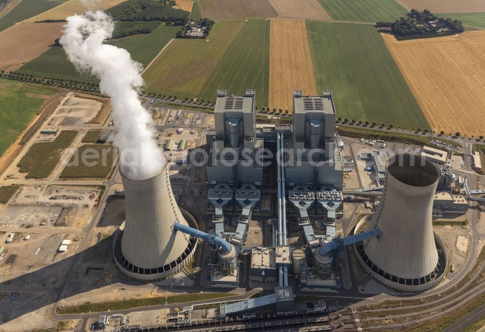 NIEDERAUßEM from above - Blick auf das Ensemble der Kohle- Kraftwerk bei Neurath und Niederaußem in Nordrhein-Westfalen. Das Kraftwerk Niederaußem ist ein von der RWE Power mit Braunkohle betriebenes Grundlastkraftwerk in Bergheim-Niederaußem (Rhein-Erft-Kreis). Der Wind treibt die aus den Kühltürmen und Schloten austretenden Rauchfahnen kilometerweit in das Umland. RWE hat am Standort in Zusammenarbeit mit Linde und BASF eine Pilotanlage zur CO2-Abscheidung aufgebaut. Ensemble of the RWE coal power plant in Neurath and Niederaussem in North Rhine-Westphalia.