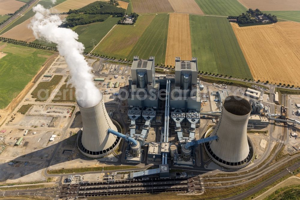 NIEDERAUßEM from the bird's eye view: Blick auf das Ensemble der Kohle- Kraftwerk bei Neurath und Niederaußem in Nordrhein-Westfalen. Das Kraftwerk Niederaußem ist ein von der RWE Power mit Braunkohle betriebenes Grundlastkraftwerk in Bergheim-Niederaußem (Rhein-Erft-Kreis). Der Wind treibt die aus den Kühltürmen und Schloten austretenden Rauchfahnen kilometerweit in das Umland. RWE hat am Standort in Zusammenarbeit mit Linde und BASF eine Pilotanlage zur CO2-Abscheidung aufgebaut. Ensemble of the RWE coal power plant in Neurath and Niederaussem in North Rhine-Westphalia.