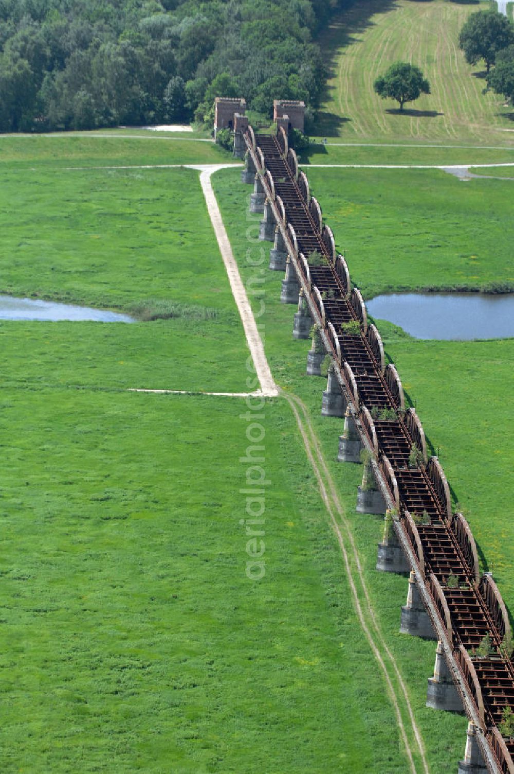 Dömitz from above - Ruine der Eisenbahnbrücke Dömitz, sie wurde in den Jahren 1870–1873 für die Wendlandbahn errichtet und bis zum Zweiten Weltkrieg befahren.An jedem Brückenende befand sich ein wehrhaft ausgebautes Brückenhaus. Starke Türme mit Zinnenkranz und Schießscharten standen beiderseits der Gleise. Im Erdgeschoss und Fundamentbereich lagen Gewölbe in kasemattenähnlicher Form. Der erste Spatenstich zum Bau der Brücke wurde am 08.09.1870 ausgeführt. Die Brücke hatte eine Gesamtlänge von 1.050 Metern. Nach ihrer Zerstörung am 20. April 1945 erfolgte kein Wiederaufbau, da die Elbe hier Teil der innerdeutschen Grenze war.