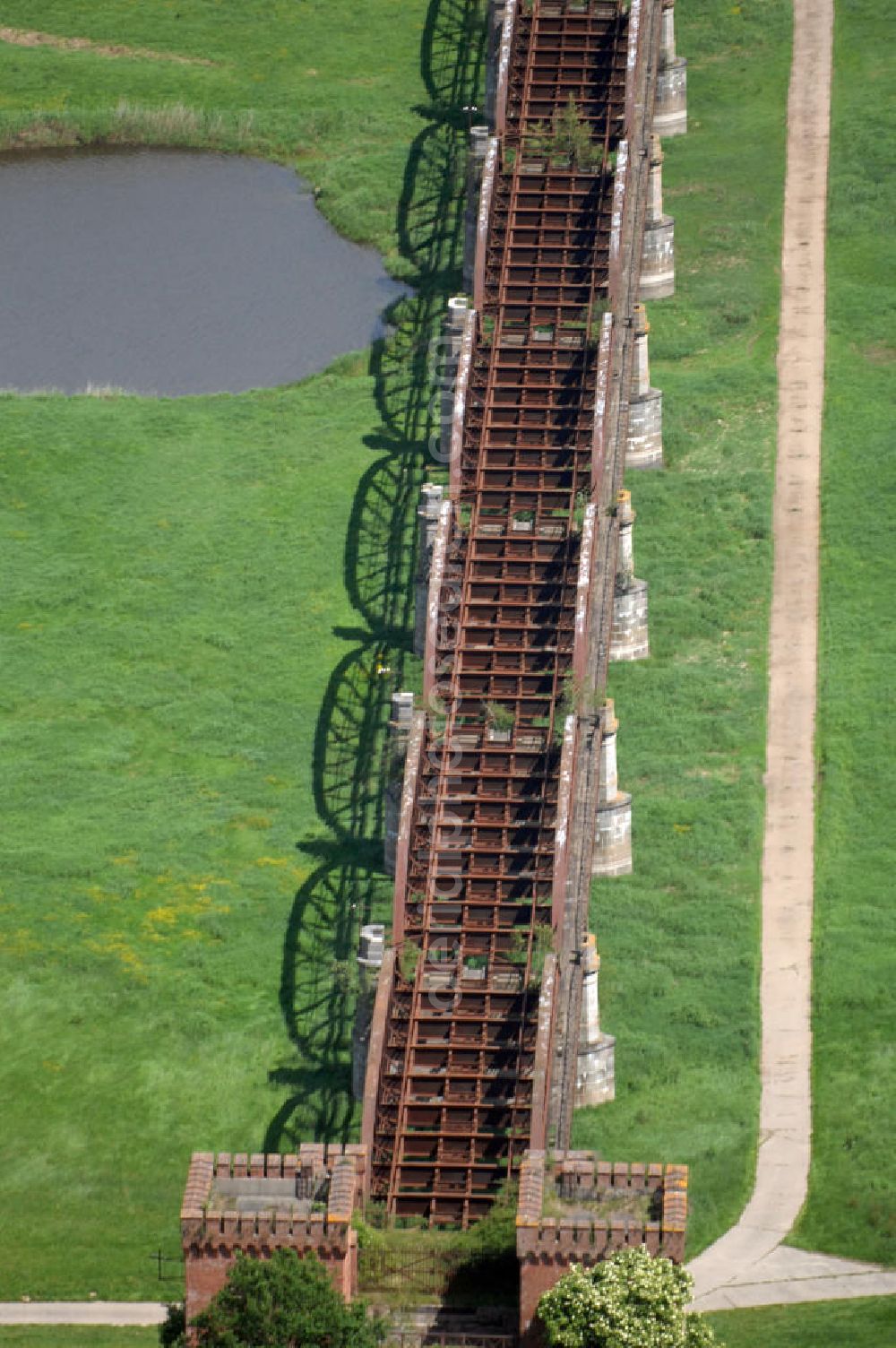 Dömitz from above - Ruine der Eisenbahnbrücke Dömitz, sie wurde in den Jahren 1870–1873 für die Wendlandbahn errichtet und bis zum Zweiten Weltkrieg befahren.An jedem Brückenende befand sich ein wehrhaft ausgebautes Brückenhaus. Starke Türme mit Zinnenkranz und Schießscharten standen beiderseits der Gleise. Im Erdgeschoss und Fundamentbereich lagen Gewölbe in kasemattenähnlicher Form. Der erste Spatenstich zum Bau der Brücke wurde am 08.09.1870 ausgeführt. Die Brücke hatte eine Gesamtlänge von 1.050 Metern. Nach ihrer Zerstörung am 20. April 1945 erfolgte kein Wiederaufbau, da die Elbe hier Teil der innerdeutschen Grenze war.