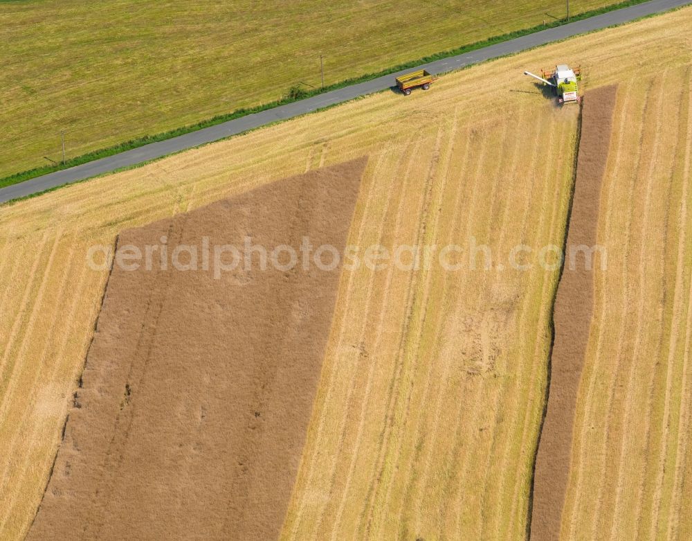 Aerial image Warstein - Harvest use of heavy agricultural machinery - combine harvesters and harvesting vehicles on agricultural fields in Warstein in the state North Rhine-Westphalia