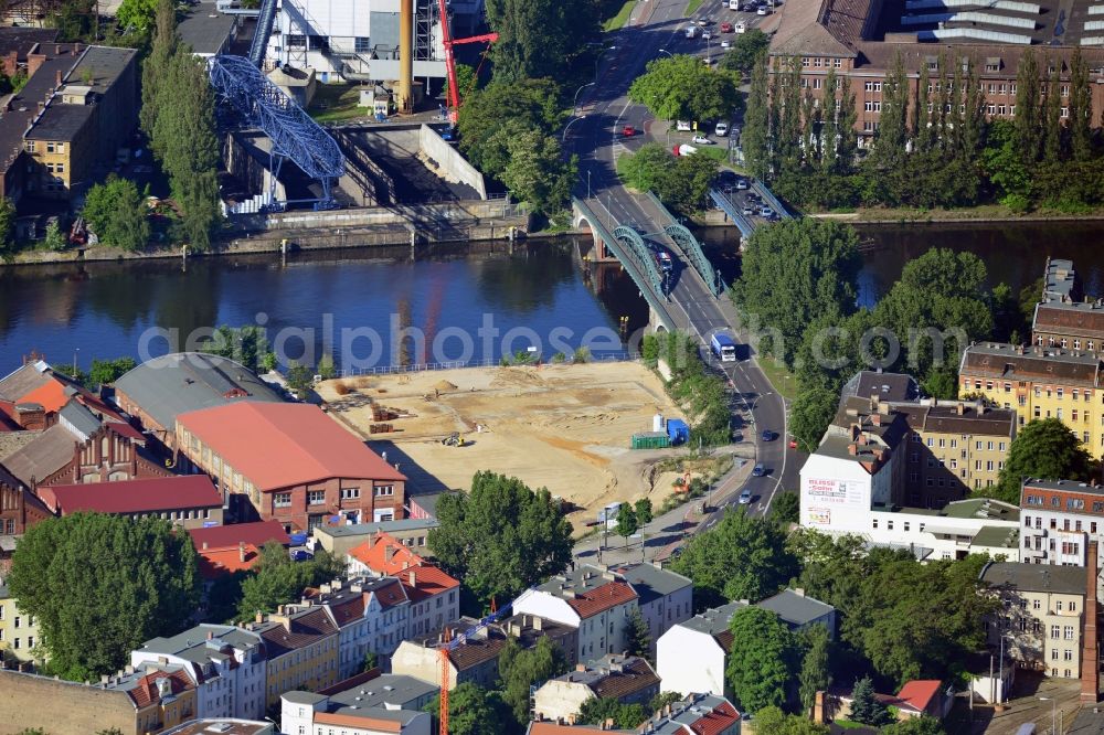 Aerial image Berlin - Construction site at the Stubenrauch Bridge in the Schöneweide part of the district of Treptow - Köpernick in Berlin. The industrial wasteland is located on Siemensstraße on the bank of the river Spree. The adjacent industrial buildings are listed as monuments. On the opposite riverbank lies the heating plant Schöneweide, one of two core facilities in the district heating system