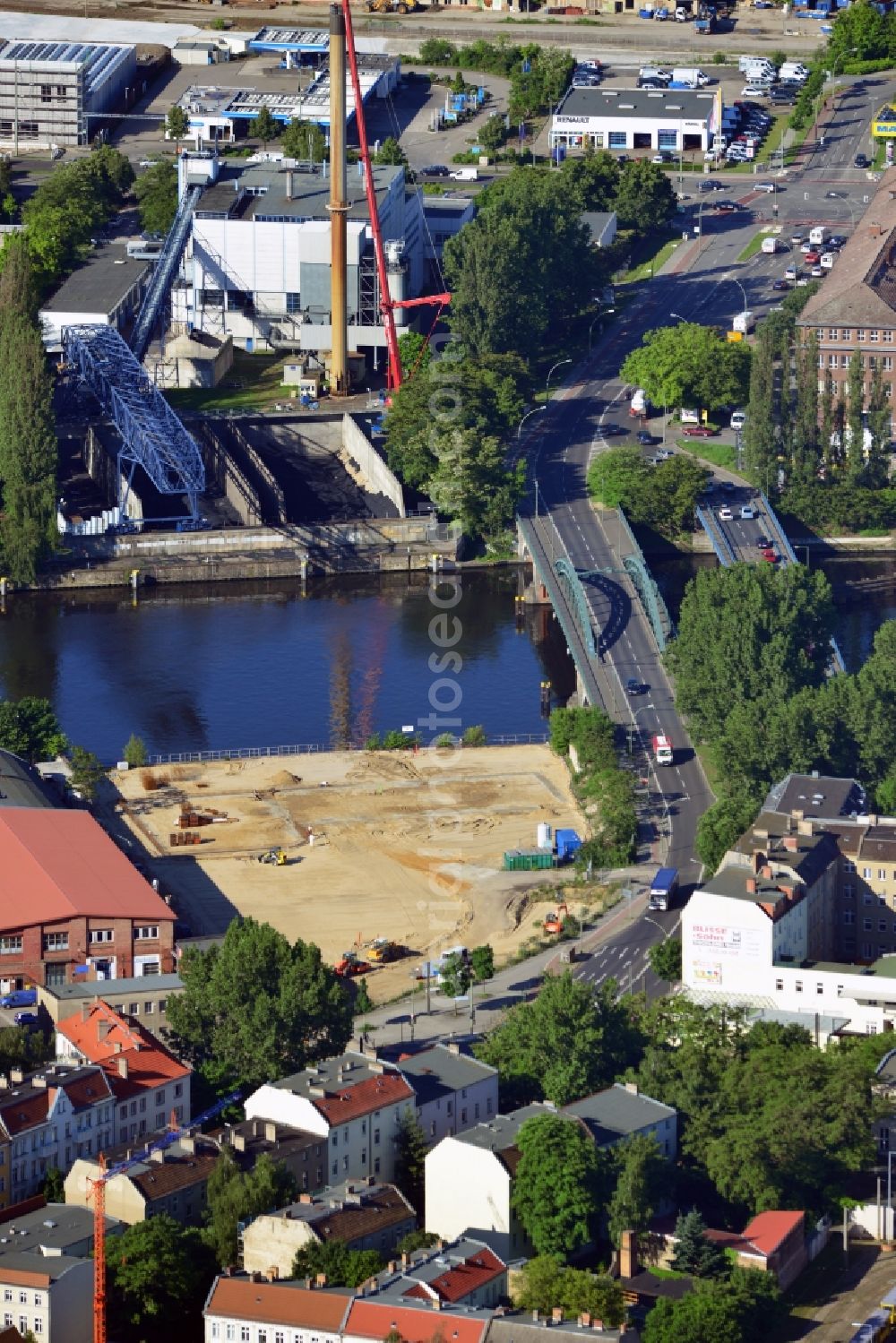 Aerial photograph Berlin - Construction site at the Stubenrauch Bridge in the Schöneweide part of the district of Treptow - Köpernick in Berlin. The industrial wasteland is located on Siemensstraße on the bank of the river Spree. The adjacent industrial buildings are listed as monuments. On the opposite riverbank lies the heating plant Schöneweide, one of two core facilities in the district heating system