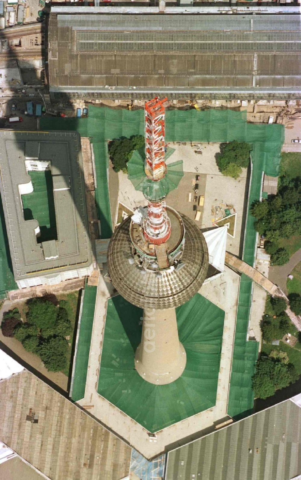 Berlin from above - Extension construction site to raise the steel mast antenna support above the shiny silver sphere of the telecommunications tower building and television tower in Mitte in Berlin, Germany