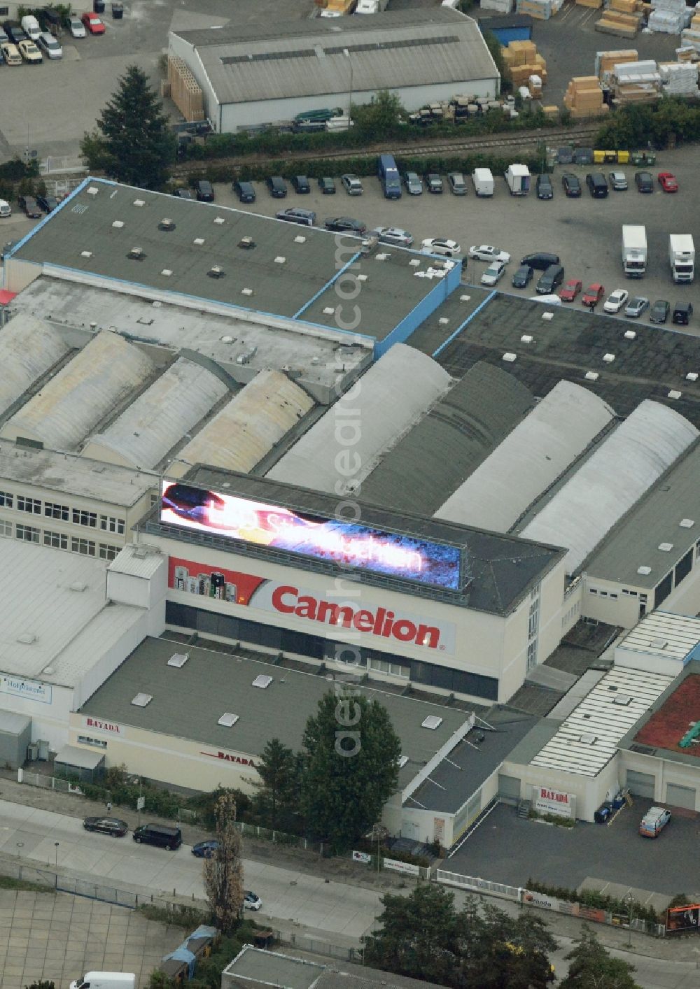 Berlin from the bird's eye view: European headquarters of the Energy- and Battery production company Camelion Batterien GmbH in Berlin in Germany. The company and factory building is located in an industrial area on Grenzallee. It is widely visible because of the luminous advertising