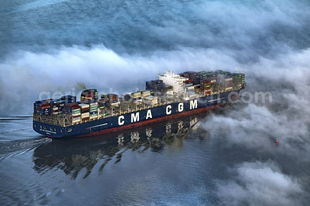 Hollern-Twielenfleth from the bird's eye view: Moving container ship CMA CGM Christophe Columb on the Elbe Hoehe Hollern-Twielenfleth in the fog in Lower Saxony, Germany