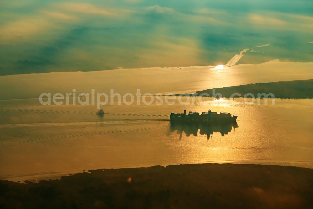 Drochtersen from the bird's eye view: Sailing container ship auf of Elbe in Sonnenaufgang in Drochtersen in the state Lower Saxony, Germany