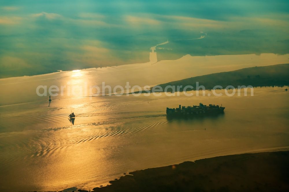 Aerial image Drochtersen - Sailing container ship auf of Elbe in Sonnenaufgang in Drochtersen in the state Lower Saxony, Germany