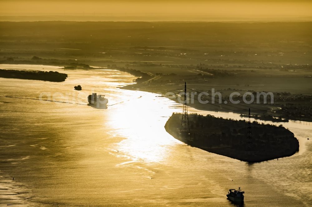 Aerial photograph Drochtersen - Sailing container ship auf of Elbe in Sonnenaufgang in Drochtersen in the state Lower Saxony, Germany