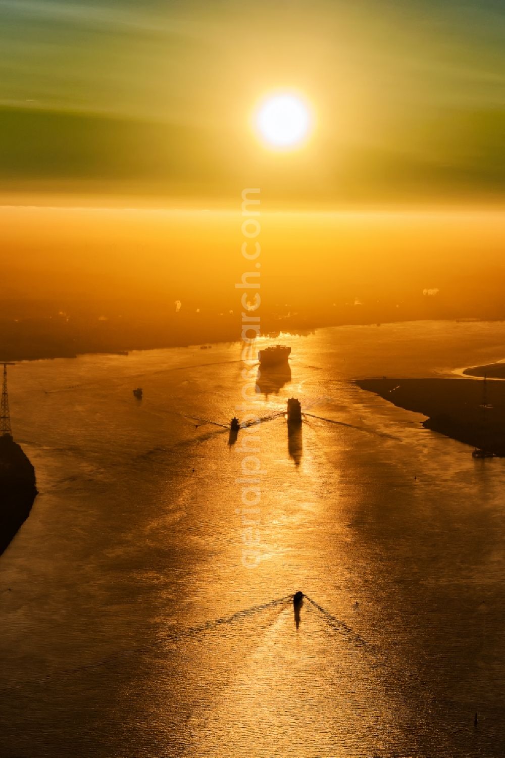 Drochtersen from the bird's eye view: Sailing container ship auf of Elbe in Sonnenaufgang in Drochtersen in the state Lower Saxony, Germany