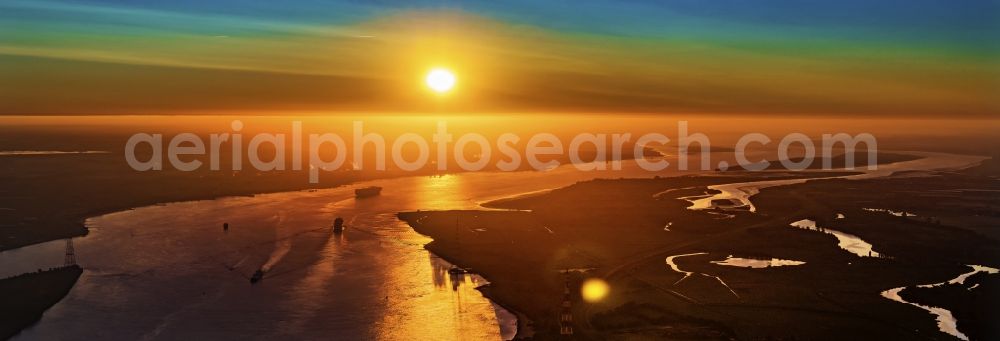 Grünendeich from the bird's eye view: Voyage of a container ship on the Elbe in the sunset in Drochtersen in the state Lower Saxony, Germany