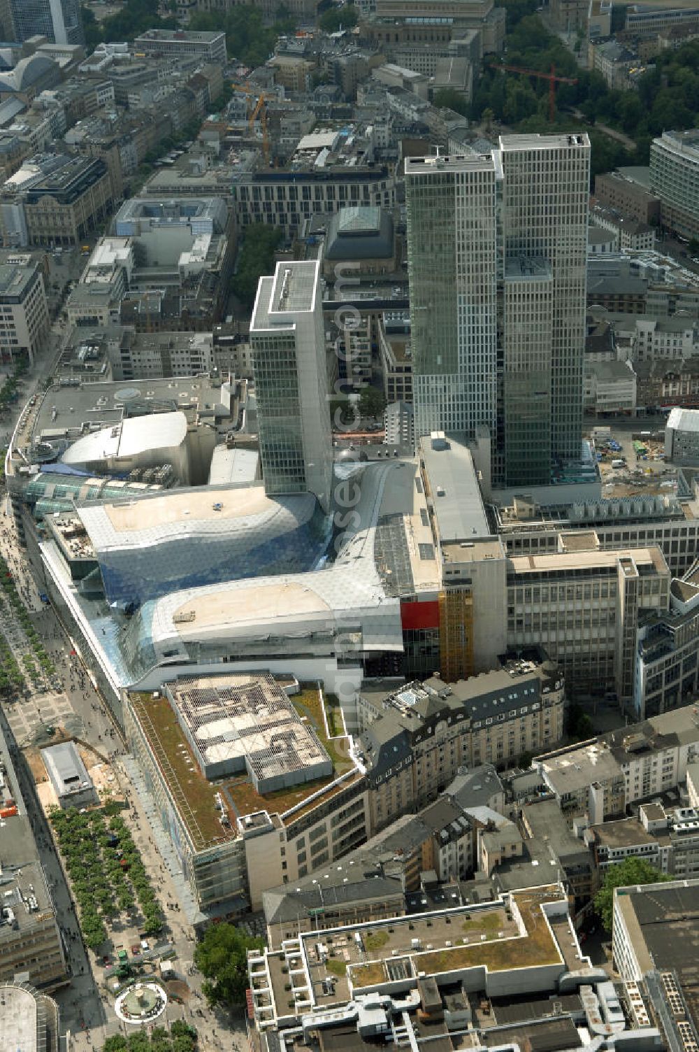 Frankfurt am Main from above - Fast fertiges Groß-Bauprojekt PalaisQuartier. Das Bauprojekt war zunächst als „Zeil-Projekt“ bekannt, danach lange Zeit als „Frankfurt Hoch Vier“ bevor mit „Palais Quartier“ der endgültige Name präsentiert wurde. Auf einer Grundstücksfläche von 17.400 qm enstehen zwei Hochhäuser ein Einkaufszentrum und ein Hotel, das nach historischem Vorbild wiedererrichtete Thurn und Taxis Palais (Schloss). Das als „Post-Areal“ bekannte Grundstück war im Februar 2002 von der Deutschen Telekom für 230 Millionen Euro an den niederländischen Investor MAB verkauft worden. Im gleichen Jahr ging das Architekturbüro KSP Engel und Zimmermann Architekten als Sieger aus dem städtebaulichen Wettbewerb für das Bauvorhaben hervor. ARGE PalaisQuartier: Dreßler Bau GmbH, Müllerstraße 26, 63741 Aschaffenburg, Tel. 06021 403 0, Fax 06021 403 216, E-Mail: ab-hv@dressler-bau.de; BAM Deutschland AG, Mönchhaldenstraße 26, 70191 Stuttgart, Tel. 0711 250 07 0, Fax 0711 250 07 150, E-Mail: Info@bam-deutschland.de; Ed. Züblin AG Albstadtweg 3, 70567 Stuttgart, Tel. 0711 7883 0, Fax 0711 7883 390, E-Mail: info@zueblin.de