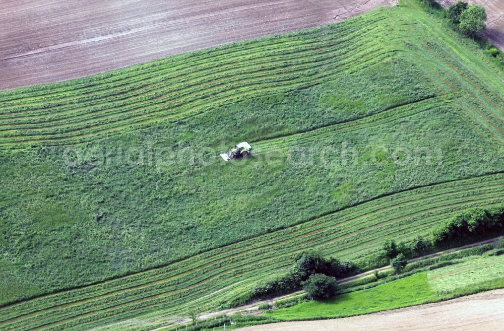 Aerial photograph Jena - On a field of Jena in Thuringia is harvested with a mower device on the tractor green stuff