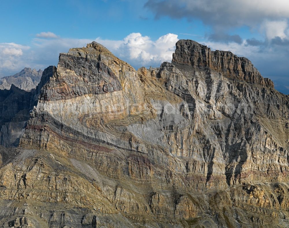 Aerial image Lavey-Morcles - Rock and mountain landscape Dent de Morcles in Lavey-Morcles in Vaud, Switzerland. The huge fold in the flank of the 2969 m high Dent de Morcles is an impressive witness of the collision between Africa and Europe. The layers, originally deposited on the sea floor in a horizontal position, were compressed and shifted. The darker parts developed during Tertiary period. They are younger than the greyish and yellowish limestone of the Cretaceous period