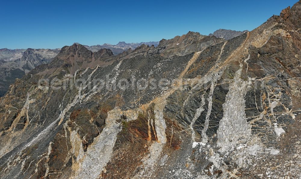 Aerial image Val Forno - Rock and mountain landscape in Val Forno in Graubuenden, Switzerland. Rock breaks during orogeny because of the enormous forces which act on the hard layers and rock masses. Cracks open deep even several hundreds and thousand meters in the undergound. Hot fluids circulate there in the hot depth of the earth, fill the cracks and cristallise when the rockformation is lifted during the orogeny and cools down. During erosion, the cracks appear as bright dykes in the dark grey and brown rock