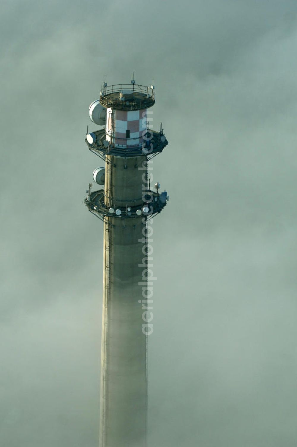 Dessau-Roßlau from the bird's eye view: Ein Fernemeldeturm / Funkturm an der Schlagbreite in Dessau-Roßlau ragt aus Wolken hervor.