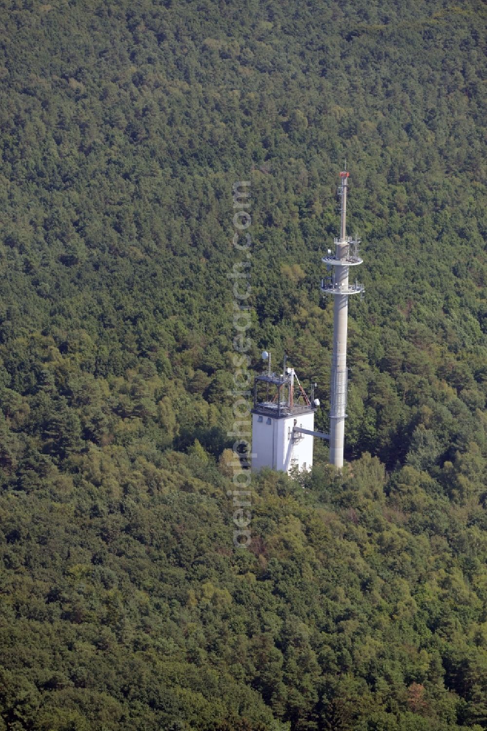 Rauen from the bird's eye view: Transmission tower radio mast of German Funkturm in the Mountains of Rauen in Rauen in the state of Brandenburg. An outbuilding with antenna stands adjacent to the actual tower. The compound is located amidst a forest