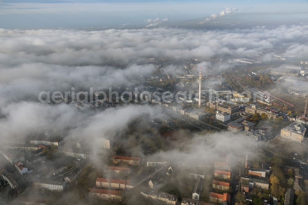 Essen from the bird's eye view: View of the area around the telecommunication tower and ETEC shrouded by fog patches and autumn weather clouds in the state North Rhine-Westphalia. The top of the television tower breaks through an impressive cloud cover over the Holsterhausen district in the Ruhr region city