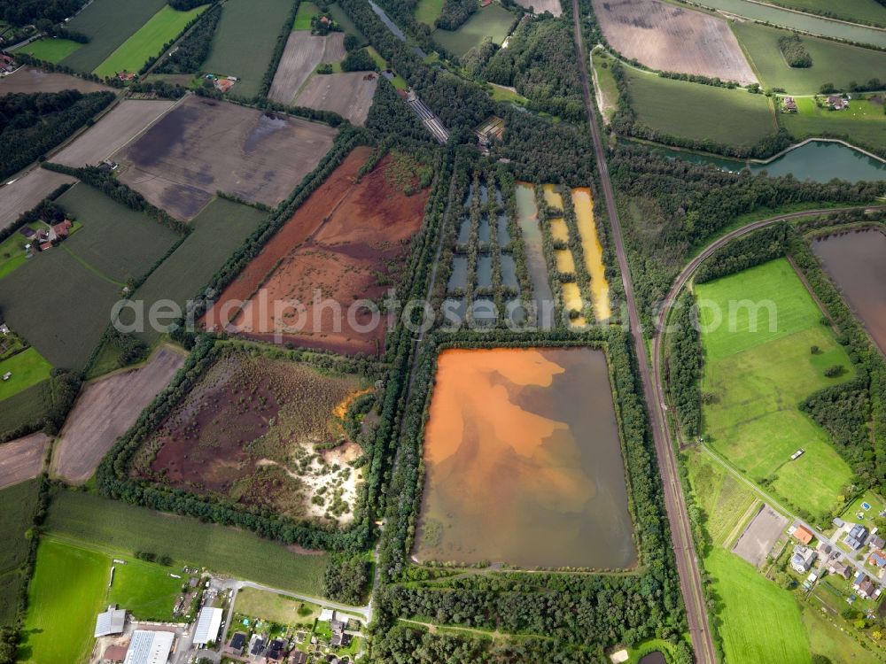 Aerial photograph Ibbenbüren - Filter pools and artificial ponds in the Puesselbueren part of Ibbenbueren in the state of North Rhine-Westphalia. The pools are located in the West of Puesselbueren and are of different sizes. The colourful water reflects the sun and clouds. The village is surrounded by such pools