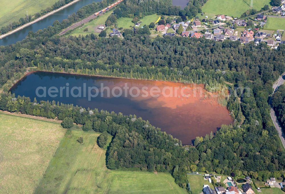 Ibbenbüren from the bird's eye view: Filter pools and artificial ponds in the Puesselbueren part of Ibbenbueren in the state of North Rhine-Westphalia. The pools are located in the West of Puesselbueren and are of different sizes. The colourful water reflects the sun and clouds. The village is surrounded by such pools