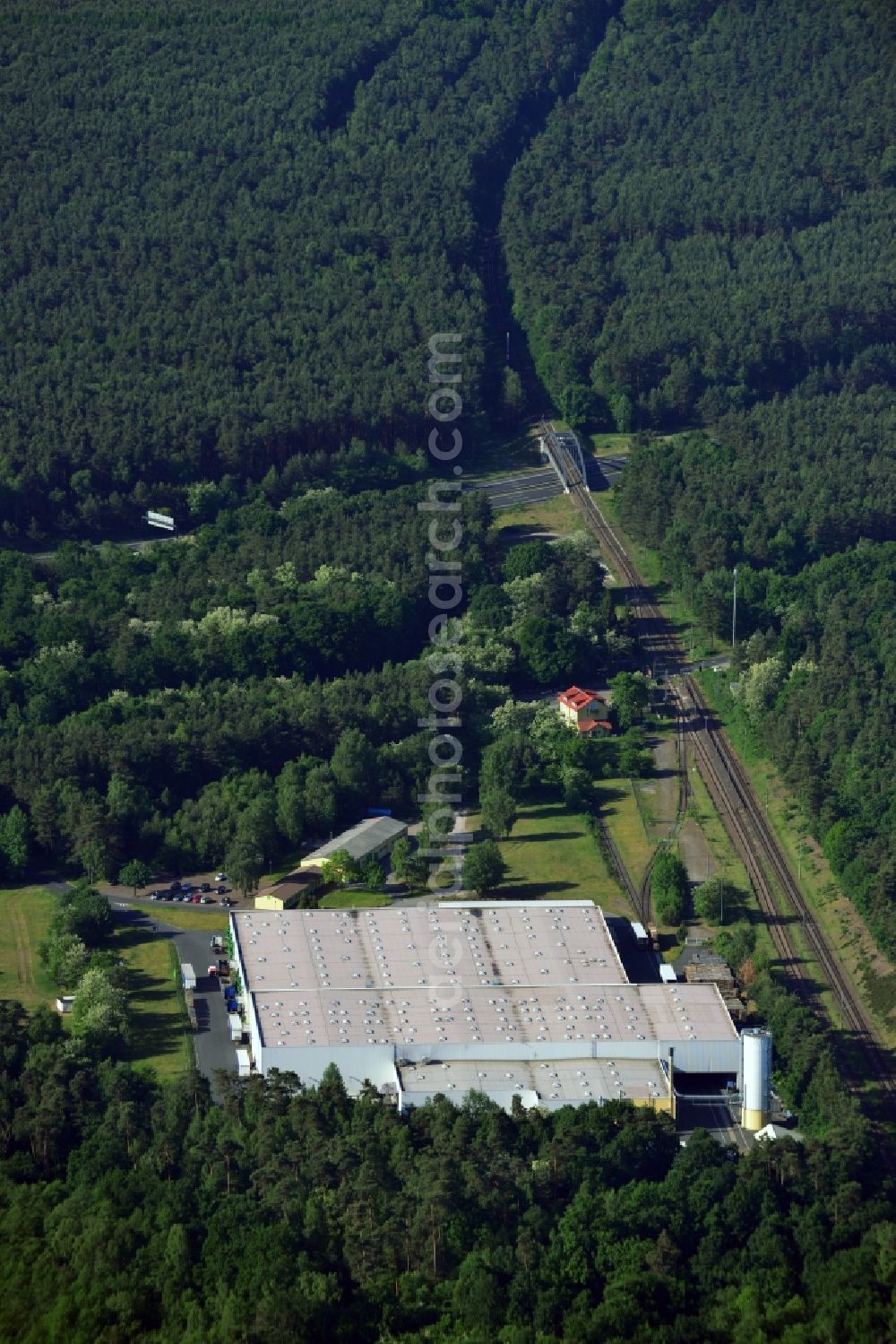 Schwielowsee from the bird's eye view: Company compound and building of Schultze Logistics GmbH in the borough of Schwielowsee in the state of Brandenburg. Schielowsee is a borough in the county district of Potsdam-Mittelmark. The company with its large hall sits in a forest on the Lienewitz train station, next to railway tracks