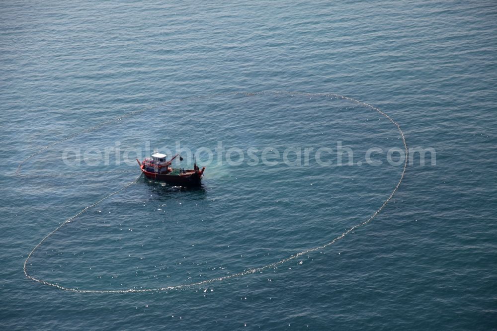 Aerial image Ratsada - Fishing boat at hauling a net on the coast of the peninsula of Laem Tukkae at Ratsada on the island of Phuket in Thailand