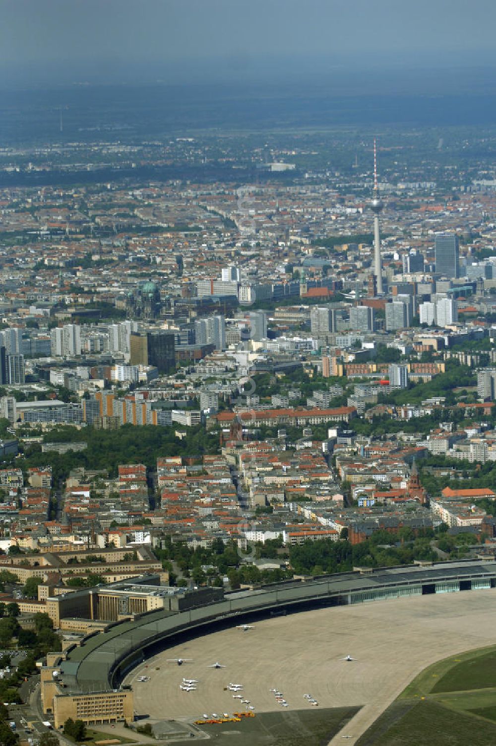 Aerial photograph Berlin - Der Flughafen Berlin-Tempelhof (IATA-Code: THF, ICAO-Code: EDDI) ist der älteste und kleinste der drei derzeit noch in Betrieb befindlichen Verkehrsflughäfen im Großraum Berlin. Um die Schließung des Flughafens doch noch zu verhindern, wurde von der Interessengemeinschaft City-Airport Tempelhof e.V. ein Volksentscheid angestrebt. Dazu wurden zunächst seit Ende November 2006 Unterschriften für die Unterstützung eines Volksbegehrens gesammelt. Am 8. Mai 2007 bestätigte der Berliner Senat die Sammlung von knapp 30.000 gültigen Unterschriften. Damit wurde der nach der Verfassung von Berlin erforderliche Nachweis von mindestens 20.000 Unterstützern für die Einleitung eines Volksbegehrens erbracht. Der nun abzuhaltende Volksentscheid wird am 27. April 2008 stattfinden. Das Ergebnis dieses Volksentscheides ist rechtlich jedoch nicht bindend, da das Volksbegehren keinen konkreten Gesetzentwurf zum Gegenstand hat, sondern lediglich eine Stimmung ausdrücken soll. Die Kosten für die Durchführung des Volksentscheides betragen etwa 2,5 Millionen Euro.[14] Auf politischer Seite setzen sich CDU und FDP für eine Ausweitung des Flugbetriebes ein; SPD, Bündnis 90-Die Grünen und Die Linke werben für ein Ende des Flugbetriebes. Ursprünglich war die Schließungs vom Berliner Senat unter einer CDU/SPD-Koalition beschlossen worden.