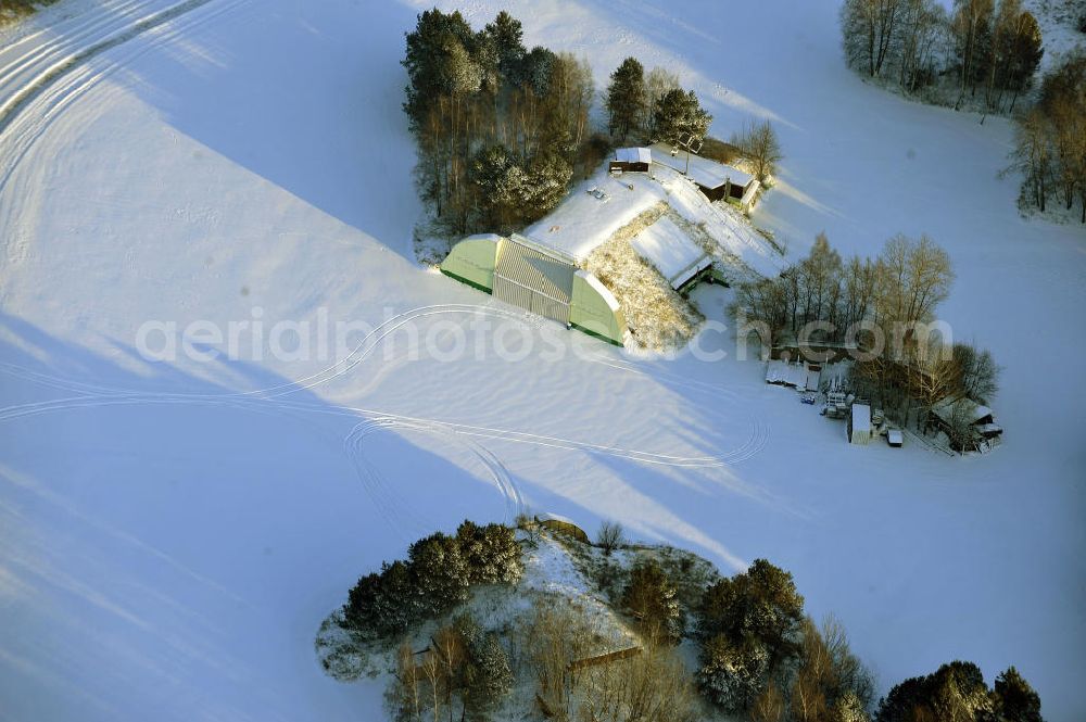 Aerial photograph Werneuchen - Zivile Nutzung / Konversion der alten Shelter / Flugzeughallen des winterlich, mit Schnee bedeckten Flugplatzes Werneuchen. Der Flugplatz diente seit den 1930er Jahren als Fliegerhorst und wurde danach von der Sowjetarmee als Flugplatz für Jagdbomber genutzt. Civilian use of the facilities of the winterly with snow-covered airfield Werneuchen.