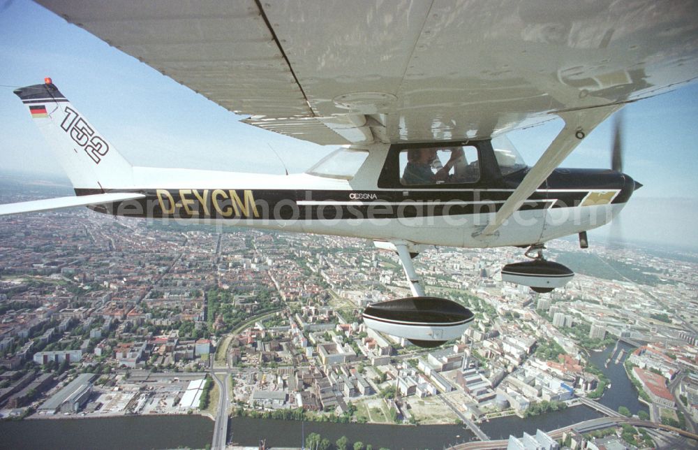 Berlin from the bird's eye view: Cessna 152 with the identifier D-EYCM Aircraft in flight over the airspace on place Alexanderplatz in the district Mitte in Berlin, Germany